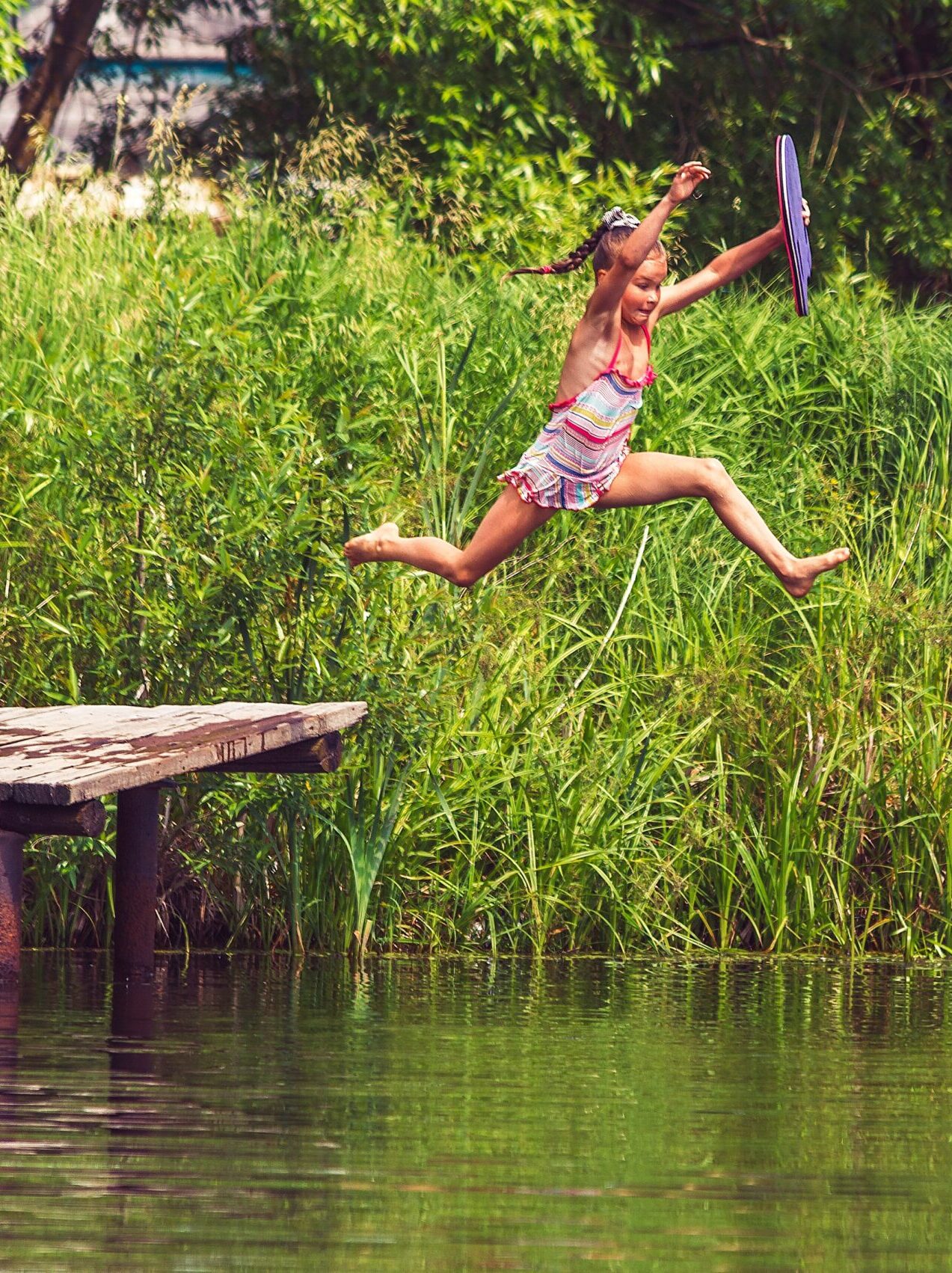 girl jumping off dock into lake
